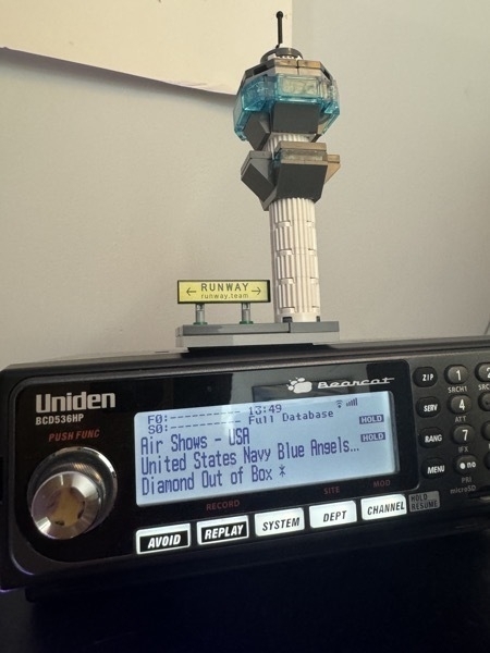 Uniden Bearcat radio receiver, tuned to the Air Show frequencies, with a mini Lego air traffic control tower sitting on top.